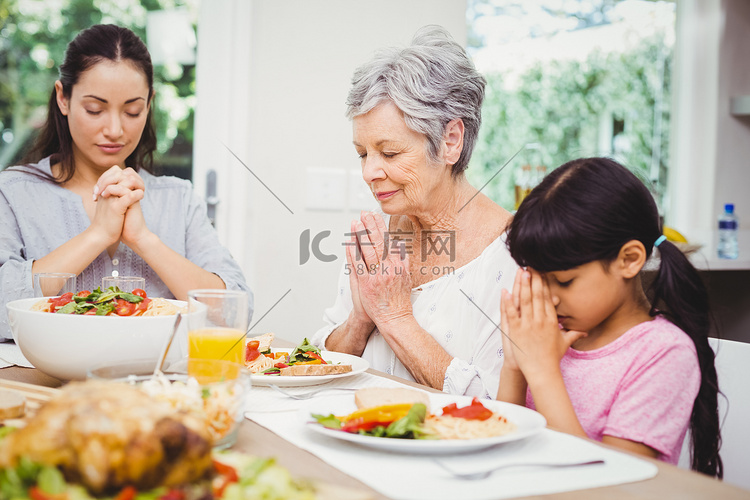 母女和奶奶在餐桌上祈祷