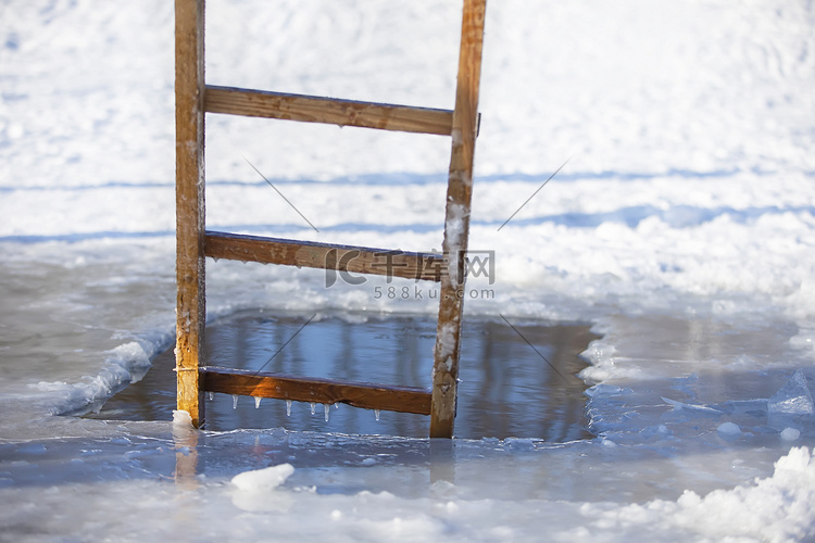 一个带木梯的冬季湖中的冰洞。