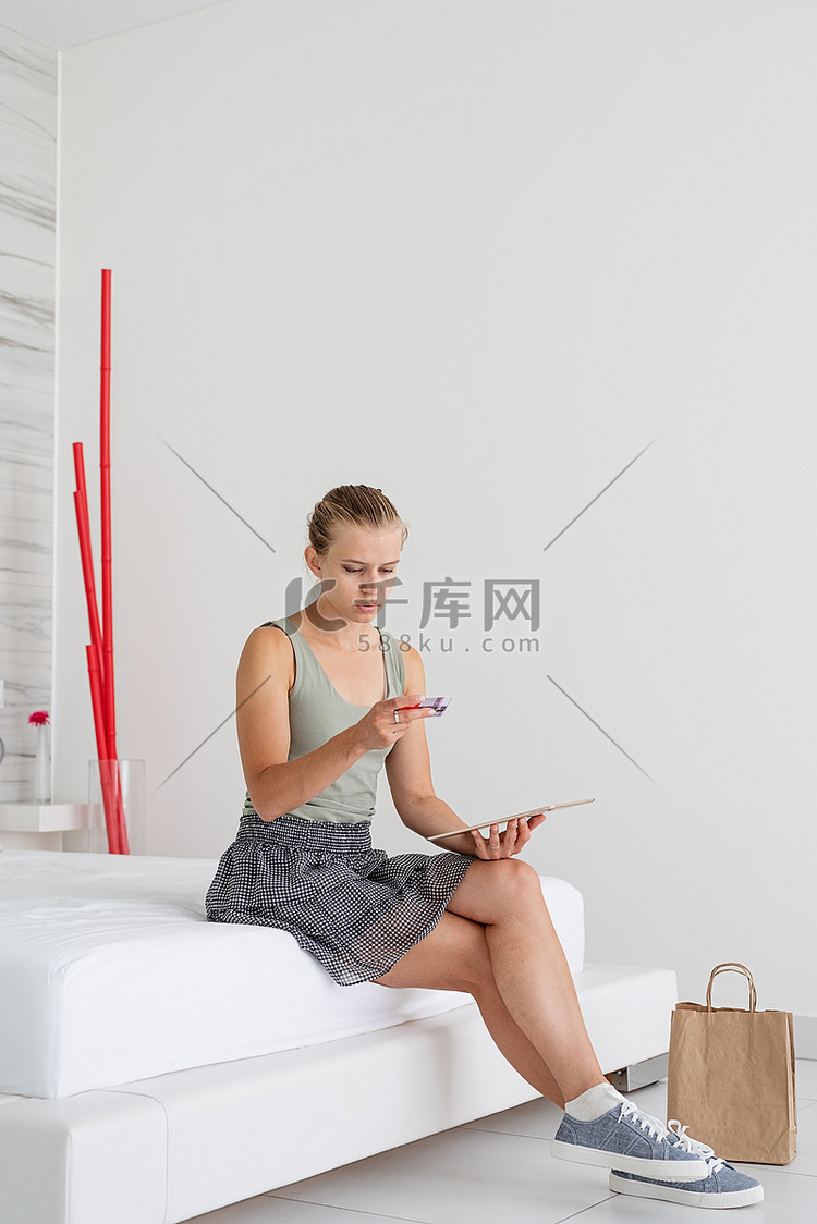 在家网上购物的年轻女性坐在床上