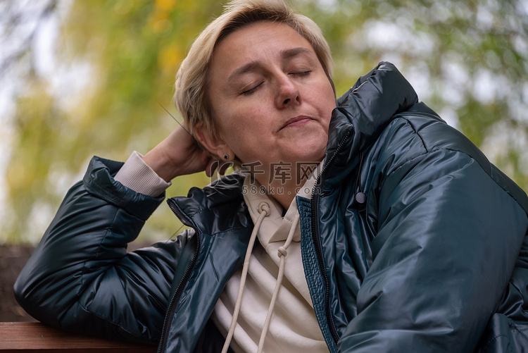 一个穿着深色夹克的女孩坐在秋天