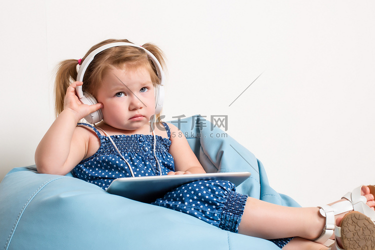 戴耳机的可爱小女孩用平板电脑听