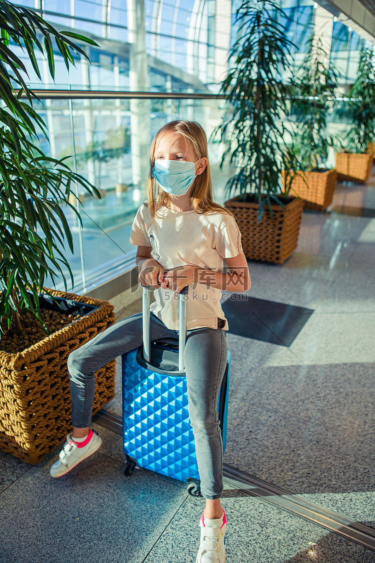 戴着医用口罩的小孩在机场等待登