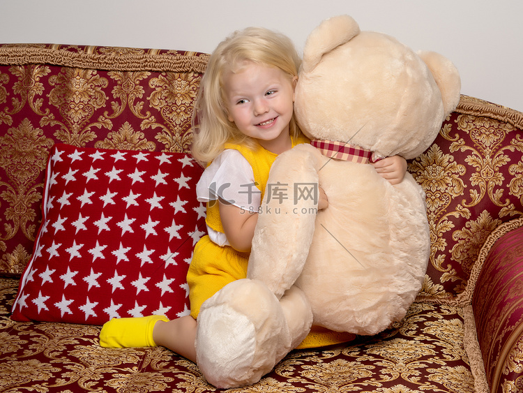 小女孩在沙发上拥抱泰迪熊。