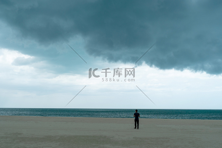 在大雨天，男人站在海滩上，乌云