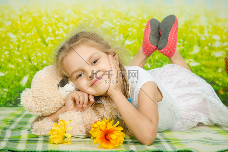 五岁女孩抱着一只躺在野餐地毯上