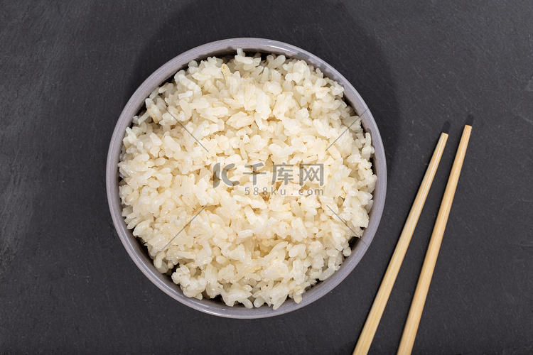 碗里的米饭和黑石板上的筷子。