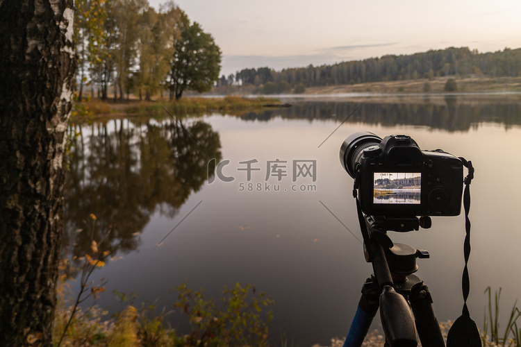三脚架上的黑色数码相机拍摄秋湖