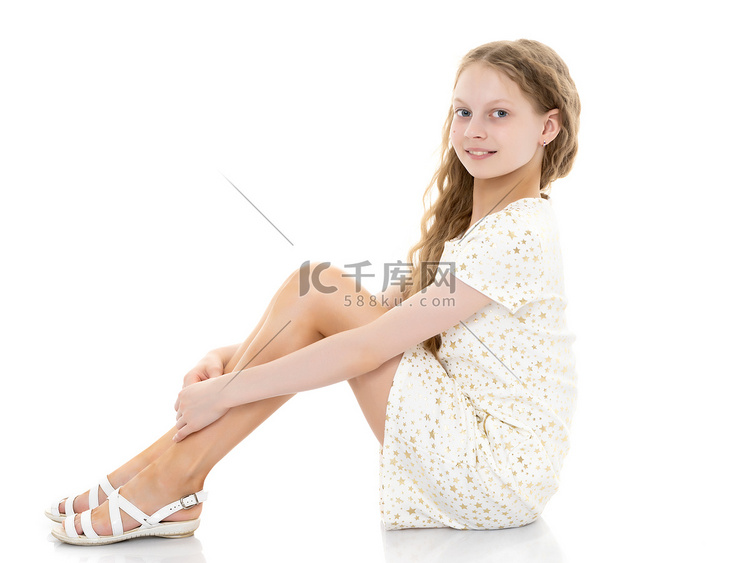 一个十几岁的女孩坐在地板上。