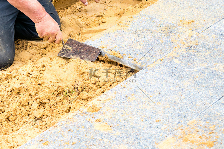 石匠在沙子上铺上碎石板，形成一