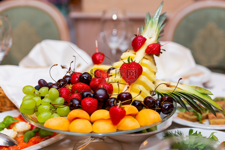 宴会桌上放着一盘水果-草莓、葡