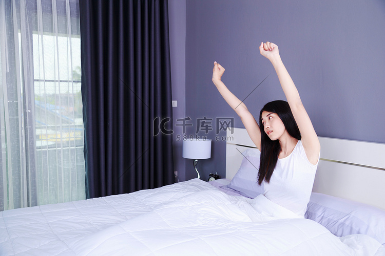 女人醒来，手举在卧室的床上