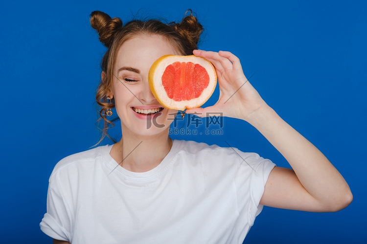 笑着的女孩惊讶地拿着柚子般的耳