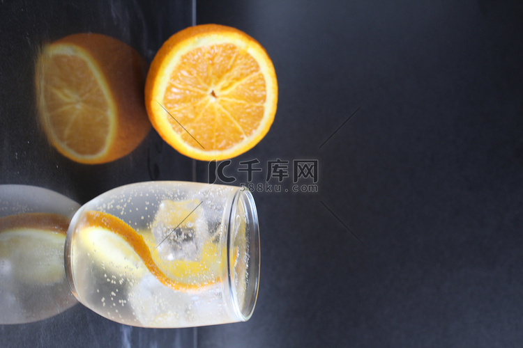 黑色背景的玻璃杯中放着橙子和冰