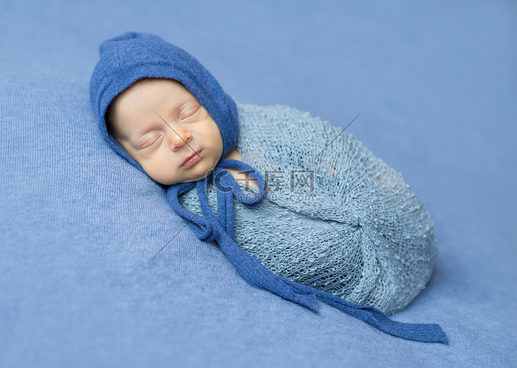 襁褓中的新生儿睡觉时头上戴着兜