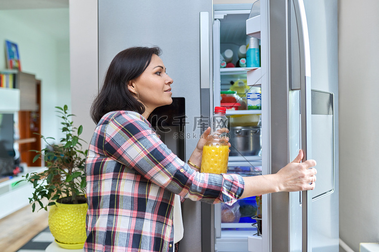一名妇女在厨房里打开家中的冰箱