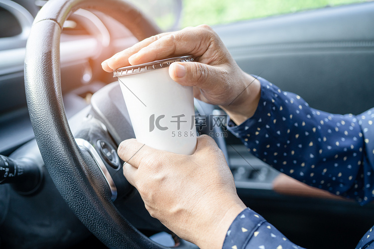 亚洲女士在车里拿着咖啡杯食物喝