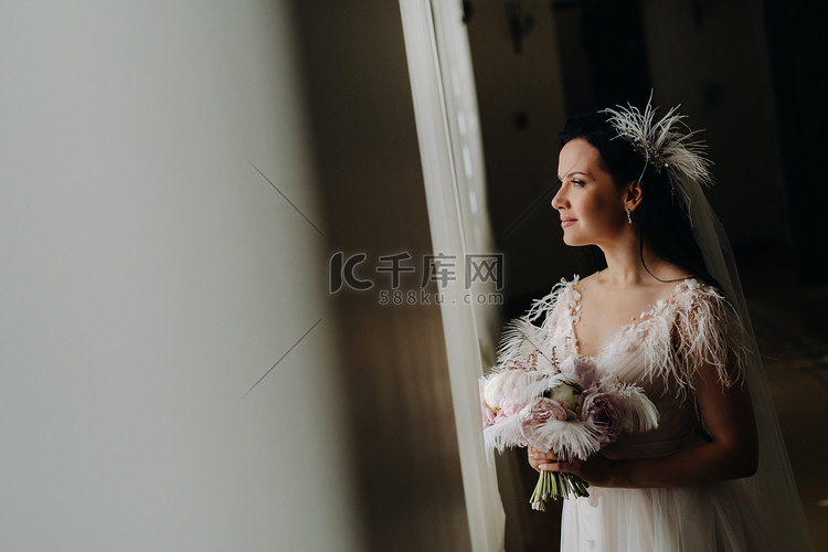 穿着婚纱和花束的新娘站在旧窗户