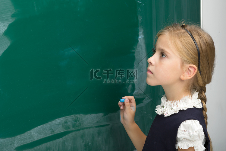 可爱的女学生在绿色黑板上写字