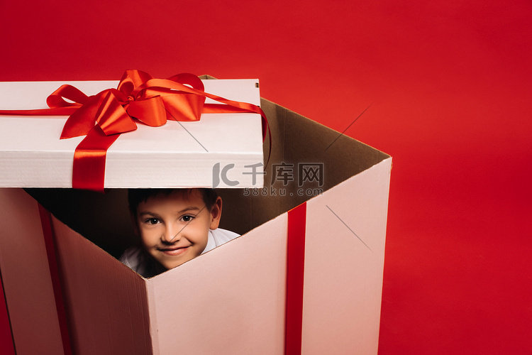 一个小男孩坐在圣诞礼物里，在红