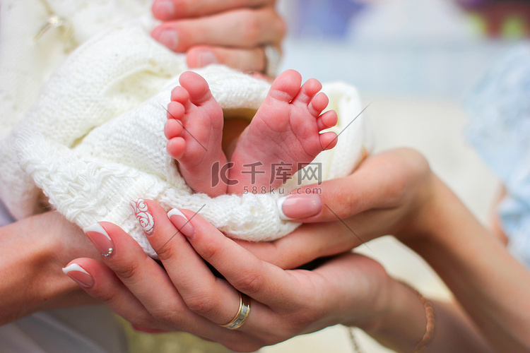 爸爸妈妈的手握着新生婴儿的小腿