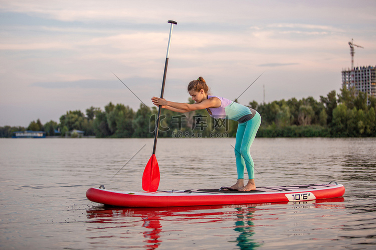 运动型女性在桨板上做瑜伽姿势，