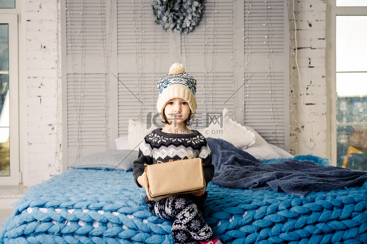 小女孩穿着睡衣，戴着帽子，坐在