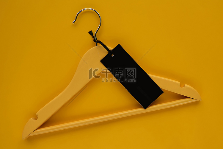 木衣架与黄纸背景上隔离的黑纸标