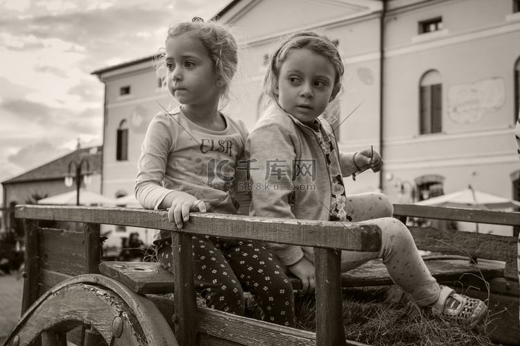 两个小女孩在一辆旧马车上玩耍的