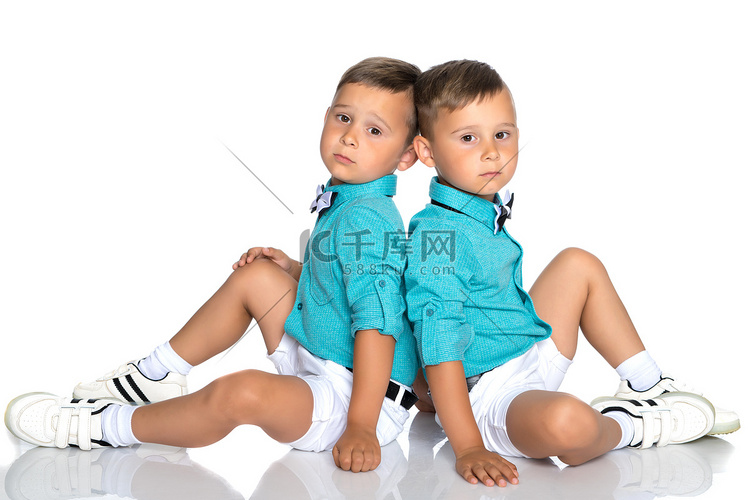 两个小男孩背靠背坐在地板上