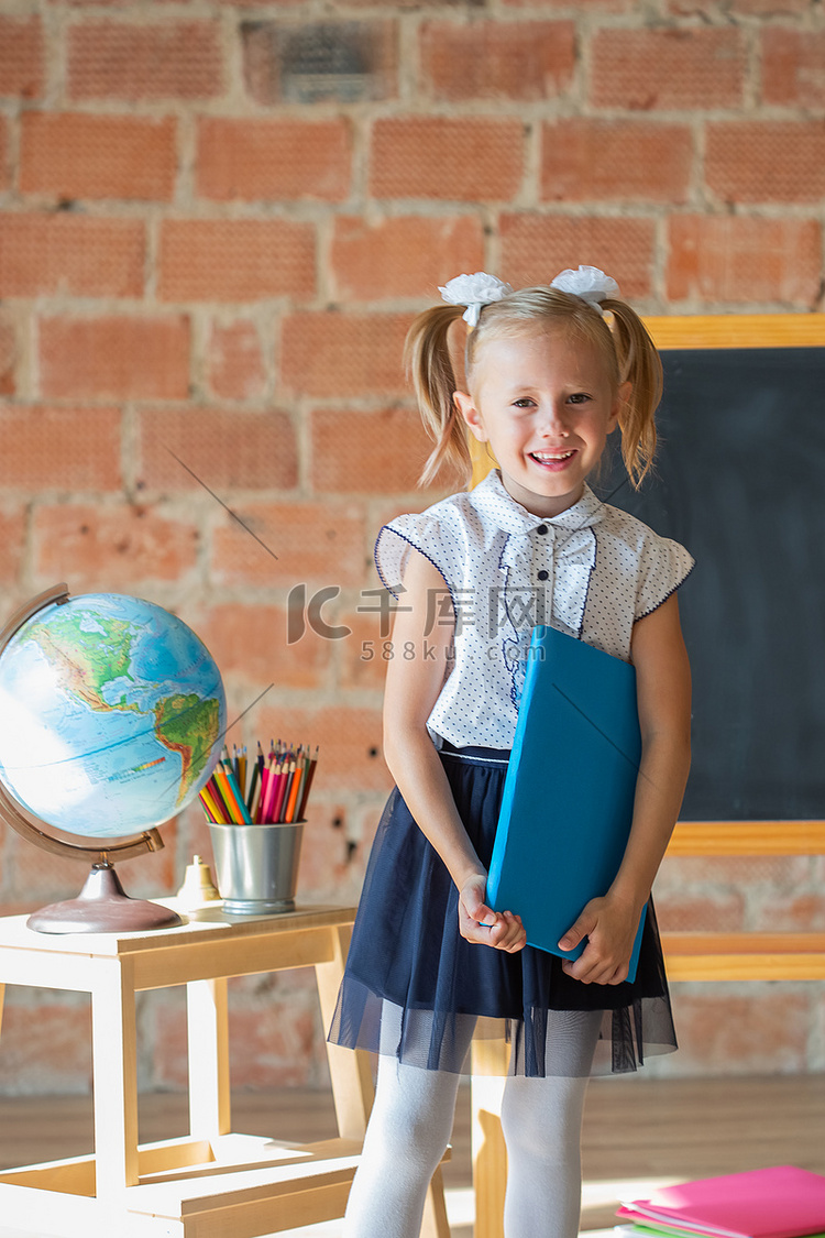 站在黑板前、手里拿着书的女学生