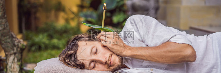 热带花园背景下进行耳烛疗法的男