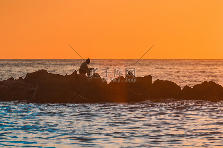 橙色夕阳下，一个孤独男子坐在海