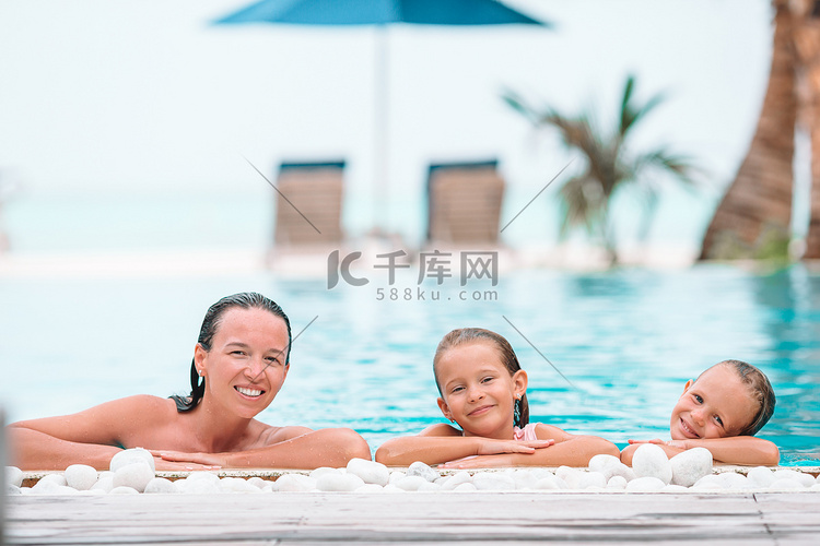 母亲和两个孩子在豪华游泳池享受