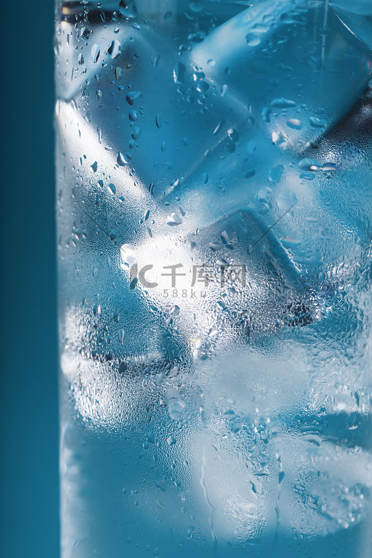 蓝色背景上装有冰水和冰块的玻璃
