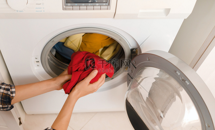 女人把鲜艳的衣服放进洗衣机。