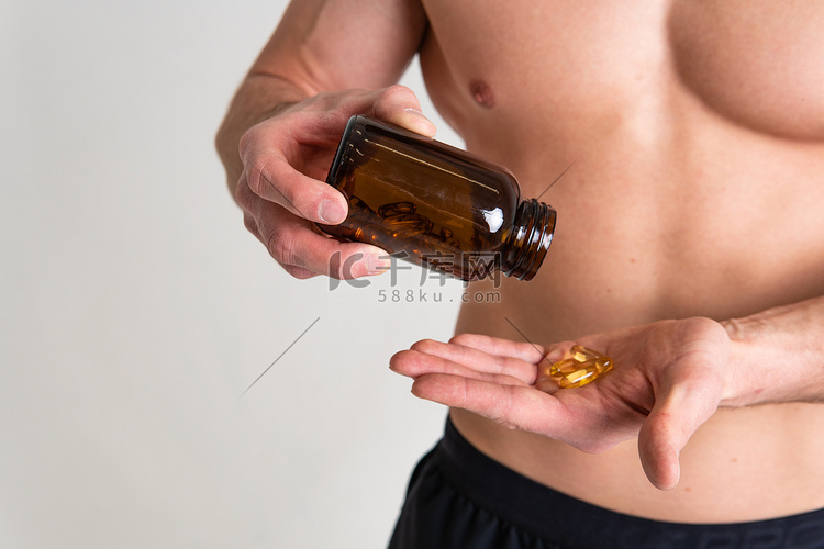 鱼油被一个男人手里的小瓶和玻璃