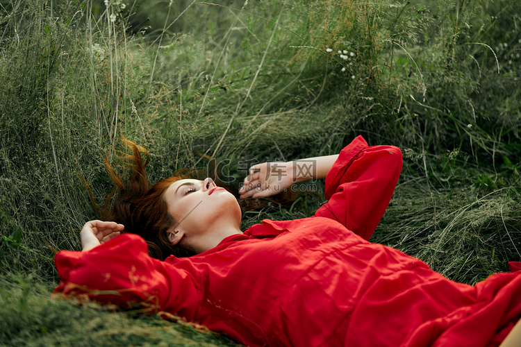 身穿红裙的漂亮女人躺在田野的草