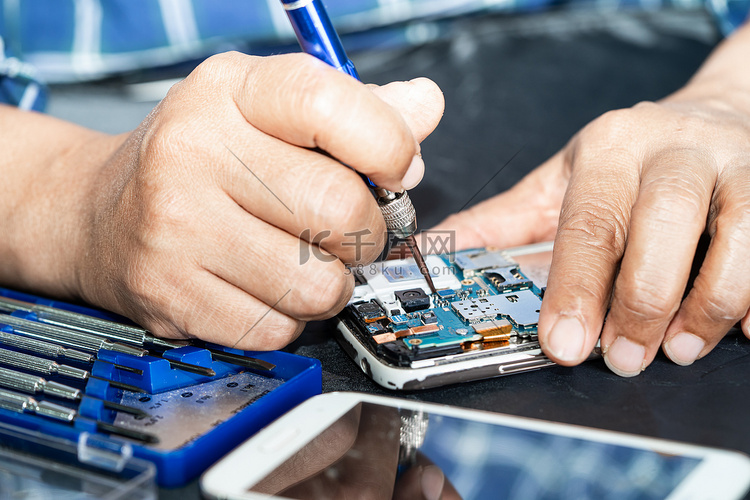 技术人员用烙铁修复手机内部。