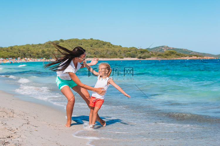 美丽的母亲和女儿在海滩享受暑假