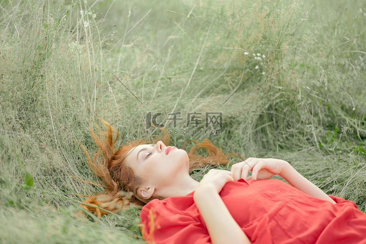 身穿红裙的漂亮女人躺在田野的草