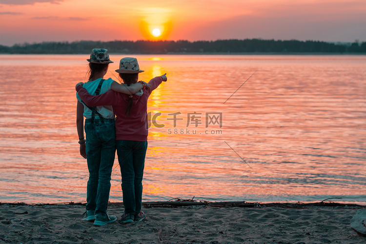 夕阳的余晖中，两个女孩姐妹站在