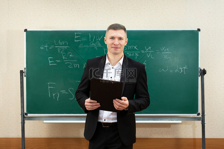 男老师在课堂上用白色粉笔在黑板