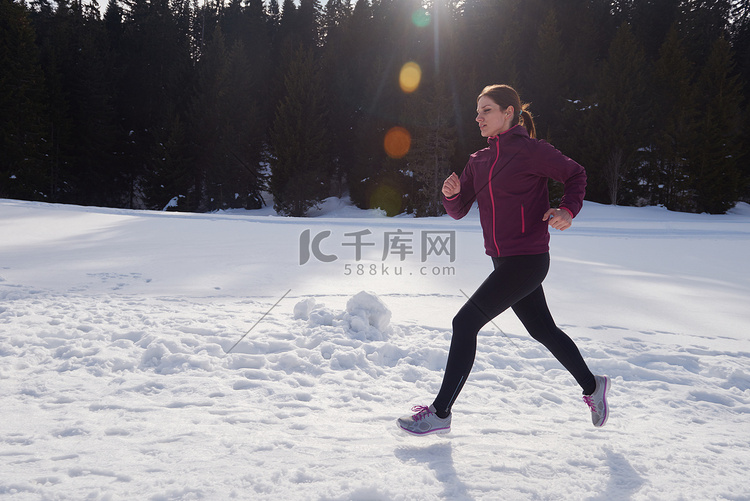 年轻女子在森林雪地户外慢跑