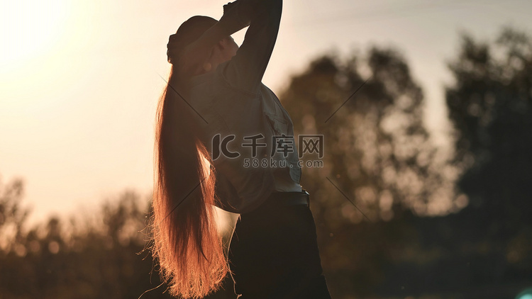 一个长发女孩在日落时的剪影。