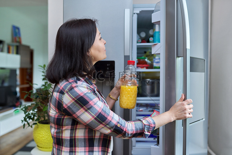 一名妇女在厨房里打开家中的冰箱
