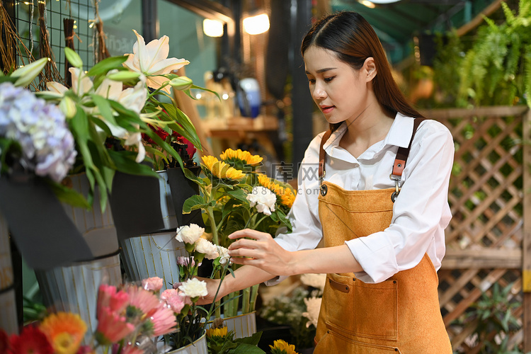 亚洲女花店穿着围裙在她质朴的花