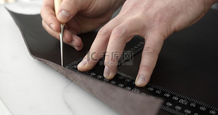 皮革工匠使用锥子和金属尺使用天