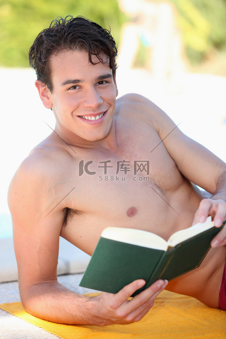 男人躺在沙滩巾上看书