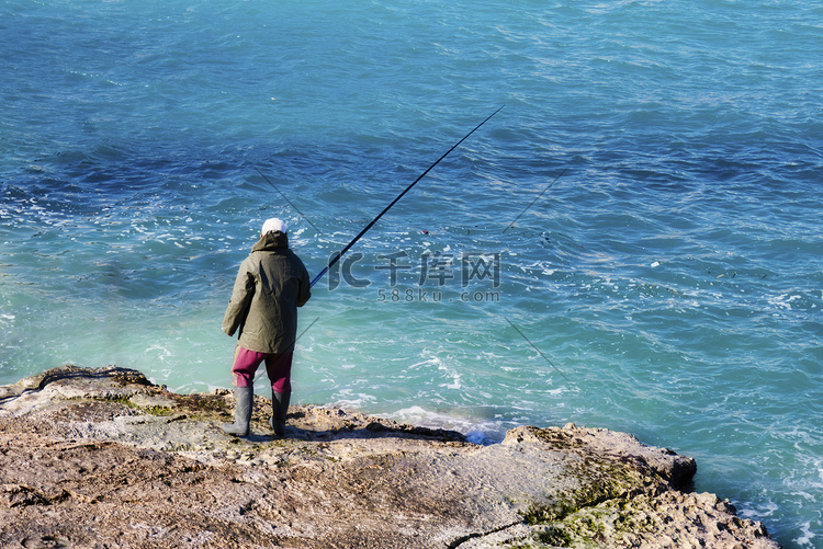 冬天，渔夫站在石滩上用竿钓鱼