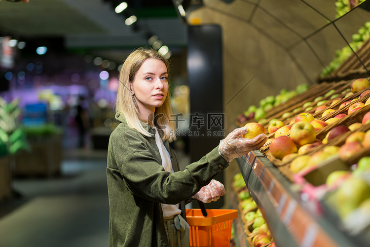年轻的金发女郎在超市柜台上挑选